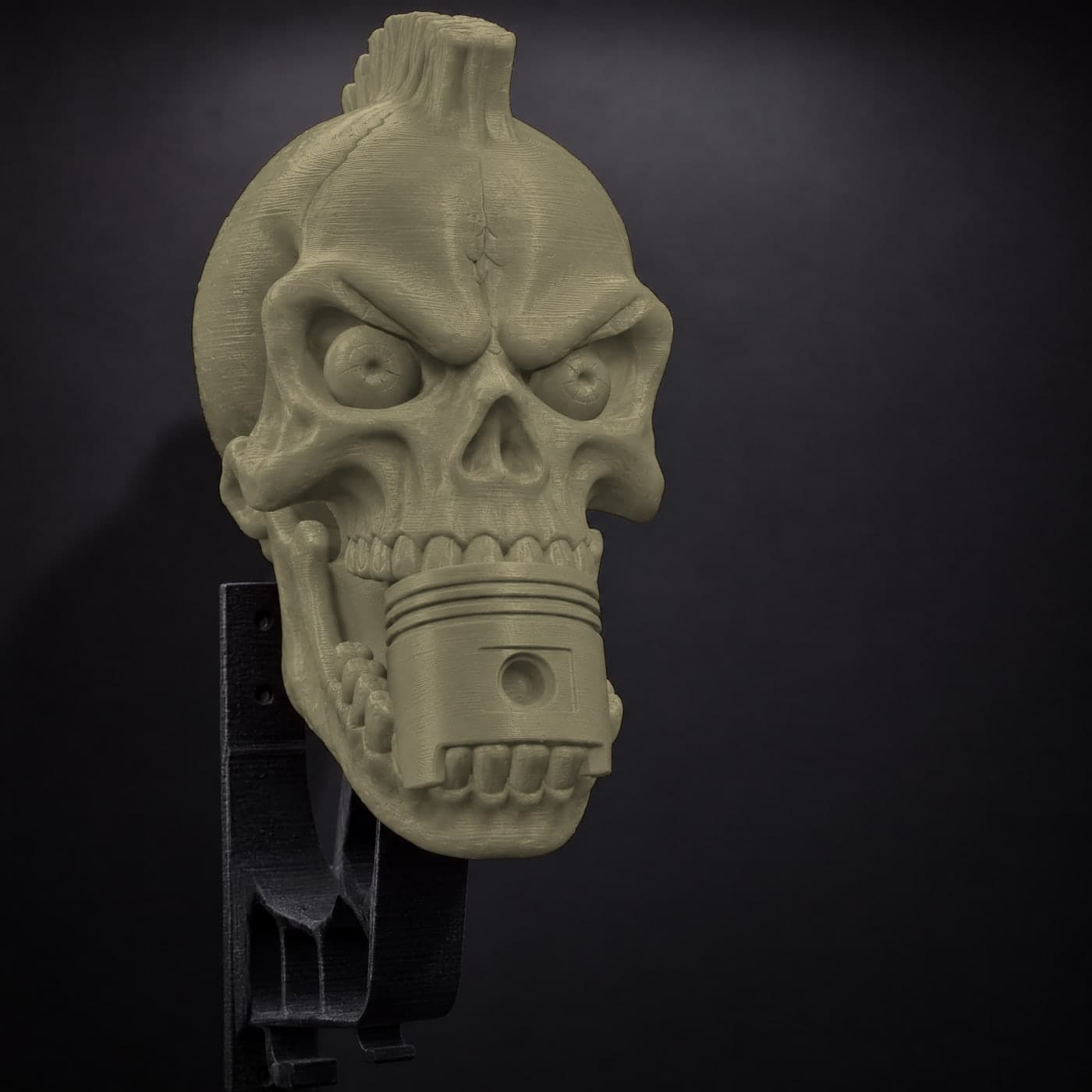 A Militia Olive piston skull, close on its face and the piston in its teeth
