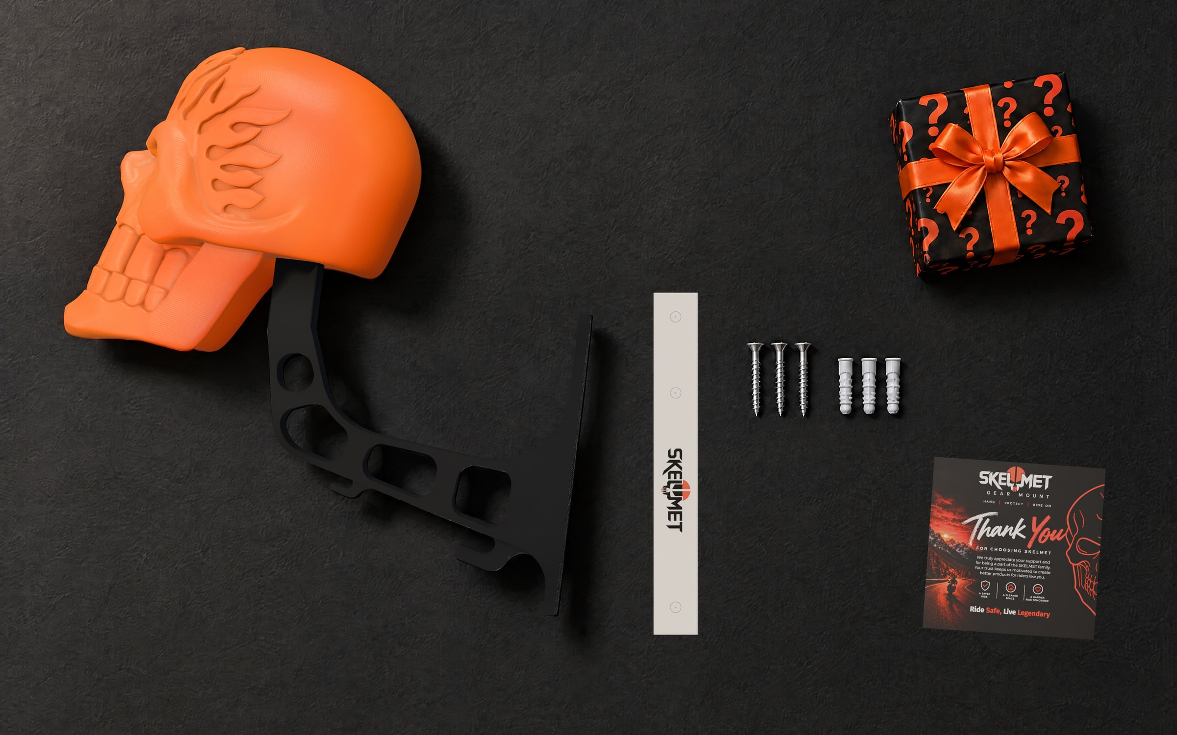 What comes in the box: the flame skull on its arm in one piece, a paper drilling guide marking the three holes, three screws and wall plugs, a thank-you card and a mystery box